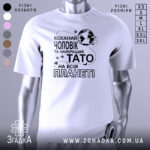 Футболка чоловік тато білого кольору, зображена з фронтального ракурсу на манекені, фон світлий, принт чорного кольору з текстом "Коханий чоловік та найкращий Тато на всій планеті" і зображенням планети.