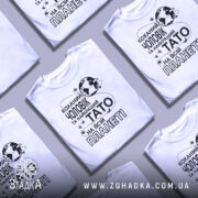 Футболка чоловік тато білого кольору, зображена з фронтального ракурсу на манекені, фон світлий, принт чорного кольору з текстом "Коханий чоловік та найкращий Тато на всій планеті" і зображенням планети.