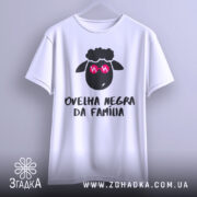 Футболка чорна вівця, біла, зображена з фронтального ракурсу на вішалці, фон світло-сірий, принт з чорним овечим обличчям у рожевих окулярах та написом 'ovelha negra da família'.
