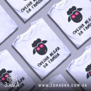 Футболка чорна вівця, біла, зображена з фронтального ракурсу на манекені, фон світло-сірий, принт з чорним овечим обличчям у рожевих окулярах та написом 'ovelha negra da família' внизу.