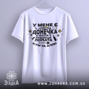 Футболка чудова донечка, біла, зображена на вішалці, фон світло-сірий, принт чорного кольору з жовтими зірками, текст українською мовою, рукави широкі.