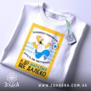 Футболка чудовий вік, біла, зображена з верхнього ракурсу, фон світлий, принт з мультфільму, на якому персонаж радісно стрибає, текст українською мовою.