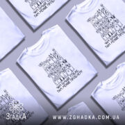 Футболка чим більше собак, біла, зображена на манекені, фон світлий, принт з малюнками собак різних порід і написом 'Чим більше собак, тим менше проблем!' у чорному кольорі.