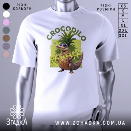 Футболка Crocodillo Ananasinno білого кольору, зображена з фронтального ракурсу на манекені, фон світло-сірий, принт з веселим ящіркою в окулярах та ананасом на голові, оточений зеленими елементами.