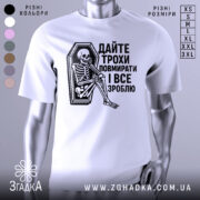 Футболка дайте трохи повмирати, біла, зображена з фронтального ракурсу, на манекені, фон світло-сірий, принт чорного кольору з малюнком скелета, що сидить у труні, текст українською мовою.