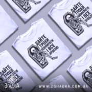 Футболка дайте трохи повмирати, біла, зображена з фронтального ракурсу, на манекені, фон світло-сірий, принт чорного кольору з малюнком скелета, що сидить у труні, текст українською мовою.