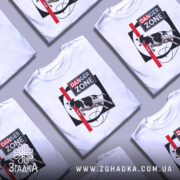 Футболка Danger Zone білого кольору, зображена на манекені, ракурс спереду, фон нейтральний, принт з коровою, червоною лінією та написом 'DANGER ZONE'.