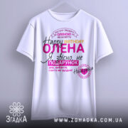 Футболка день народження, біла, підвішена на вішалці, фон світло-сірий, принт з текстом на українській мові, кольори: рожевий, жовтий, чорний, фіолетовий.