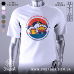 Футболка день обміну не підлягає. Біла футболка з коротким рукавом, зображена з фронтального ракурсу. На фоні світло-сірий колір. Принт містить кольорові зображення чайника, чашки та гір, оформлені в стилі графіки.