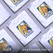 Футболка дякую за п`ятницю, біла, зображена на манекені, фон світло-сірий, принт зображає жінку в хустці, яка тримає палець на губах, кольори принта жовтий, синій та оранжевий.