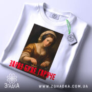 Футболка діджей дівчина, біла, зображена зверху, фон світлий, принт з портретом дівчини в навушниках, текст червоним шрифтом 'ЗАРАЗ БУДЕ ГАРЯЧЕ', на комірці видно етикетку.