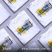 Футболка дім Україна, біла, зображена на манекені, фон нейтральний, принт містить жовто-блакитний колір, зображення соняшника та графічні елементи.