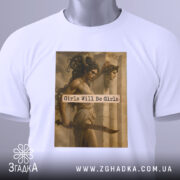 Футболка дівчата можуть бути білого кольору, складена на поверхні з видимим етикеткою. Принт з зображенням двох жінок та текстом "Girls Will Be Girls" займає центральну частину футболки.