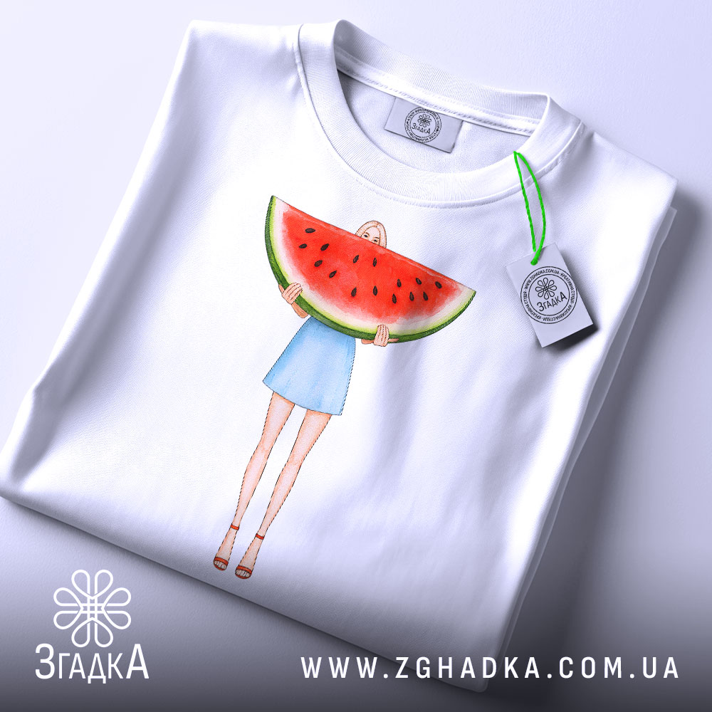 Футболка дівчина кавун, біла, з верхнього ракурсу, на фоні світло-сірого, принт з дівчиною у блакитній спідниці, яка тримає кавун, з етикеткою на шнурку.