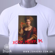 Футболка дівчина піца, біла, зображена на столі, фон світло-сірий, принт з портретом жінки в червоній сукні, яка тримає шматок піци, текст "Хочу, можу, їм" червоним шрифтом, з етикеткою на комірці.