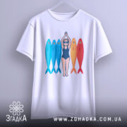 Футболка дівчина рибки білого кольору, підвішена на вішалці, фон світло-сірий, принт з дівчиною в купальнику та рибками, які мають блакитний та червоний кольори, зображення чітке та яскраве.