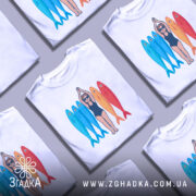 Футболка дівчина рибки білого кольору, зображена з фронтального ракурсу на манекені, фон світло-сірий, принт з дівчиною в купальнику та рибками різних кольорів: блакитними, червоними та жовтими.