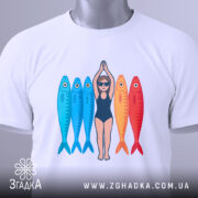 Футболка дівчина рибки білого кольору, зображена зверху, на ній видно принт з дівчиною в купальнику та рибками, які мають яскраві кольори: блакитний та червоний, на футболці є етикетка з зеленим шнурком.