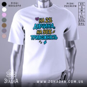 Футболка дівчина тривожність подарунок. Біла футболка на манекені, з принтом на грудях, текст кольоровий: 'НА 2% ДІВЧИНА, НА 98% ТРИВОЖНІСТЬ'. Фон світло-сірий, акцент на принті.