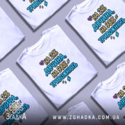 Футболка дівчина тривожність подарунок. Білі футболки, складені одна на одну, з кольоровим принтом 'НА 2% ДІВЧИНА, НА 98% ТРИВОЖНІСТЬ'. Фон світло-сірий, акцент на тексті.