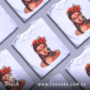 Футболка Дівчина Войовниця, біла, зображена на манекені, фон світло-сірий, принт з зображенням дівчини з червоними квітами на голові та мечем, вираз обличчя серйозний, червона смужка на лобі.