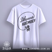 Футболка дівчина з космосу, біла, підвішена на вішалці, фон світло-сірий, принт чорний з написом 'Дівчина з космосу' та малюнком астронавта.