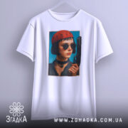 Футболка дівчина з пістолетом, біла, з бокового ракурсу, на фоні світло-сірого кольору, принт з зображенням дівчини в червоній шапці та чорних окулярах, тримає пістолет.