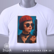 Футболка дівчина з пістолетом, біла, з верхнього ракурсу, на фоні світло-сірого кольору, принт з зображенням дівчини в червоній шапці та чорних окулярах, пістолет у руці, з етикеткою на шнурку.