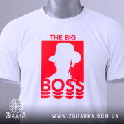 Футболка для босса, білого кольору, складена на столі, фон світло-сірий, принт червоного кольору з написом 'THE BIG BOSS' та силуетом людини в капелюсі, на футболці прикріплена етикетка.