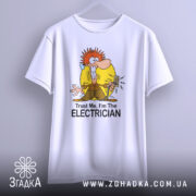 Футболка для електрика білого кольору, зображена на вішалці, фон світло-сірий, принт з мультяшним персонажем з червоним волоссям, що тримає електричний вимикач, текст "Trust Me, I'm The ELECTRICIAN" під малюнком.