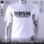 Футболка для маркетолога, білого кольору, зображена на манекені з блискучою поверхнею, фон світло-сірий, принт чорного кольору з написом 'BDSM BUSINESS DEVELOPMENT SALES & MARKETING'.