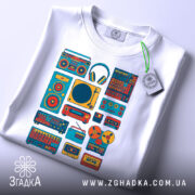 Футболка для меломана, білого кольору, зображена на столі, фон світло-сірий, принт з музичними елементами в яскравих кольорах, на футболці також видно етикетку з логотипом.