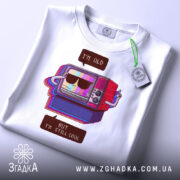 Футболка для олдів, білого кольору, зображена зверху, фон світло-сірий, принт з телевізором у ретро стилі, на футболці є етикетка з логотипом.