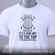 Футболка для рокера, біла, складена на поверхні, фон світлий, принт чорного кольору з текстом "IT'S A LONG WAY TO THE TOP (IF YOU WANNA ROCK 'N' ROLL)" та графічними елементами, на футболці підвісна етикетка.