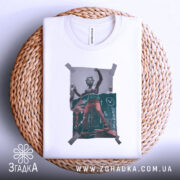 Футболка для скейтерів, біла, складена на кошику з ротангу, фон світло-сірий, принт з малюнком скейтера в червоних штанах, обклеєний скотчем.