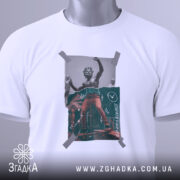 Футболка для скейтерів, біла, складена на поверхні, фон світло-сірий, принт з малюнком скейтера в червоних штанах, обклеєний скотчем, з етикеткою зеленого кольору.