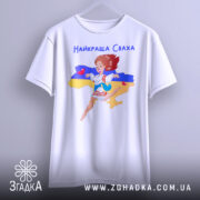 Футболка для свахи білого кольору, підвішена на вішалці, фон нейтральний, принт з дівчиною в українському вбранні на фоні карти України, з жовтою та синьою смугами.