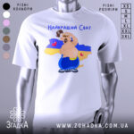 Футболка для свата, біла, зображена на манекені, фон нейтральний, принт з веселим персонажем на фоні карти України, текст 'Найкращий Сват' зверху, сердечка на карті.