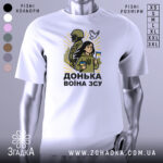 Футболка донька воїна ЗСУ, білого кольору, зображена на манекені, фон світло-сірий, принт з дівчиною, солдатом та голубом, яскраві жовті промені навколо.