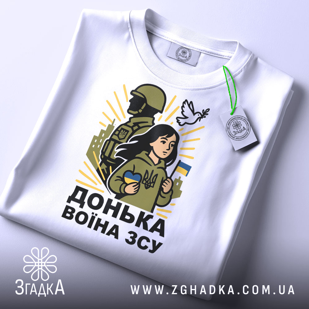 Футболка донька воїна ЗСУ, білого кольору, зображена зверху, фон світло-сірий, принт з дівчиною, солдатом та голубом, на футболці є етикетка з зеленим шнурком.