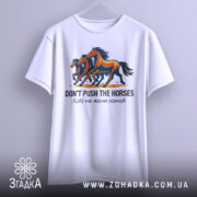 Футболка don't push the horses, білого кольору, підвішена на вішалці, фон світло-сірий, принт з трьома конями, кольори принта - коричневий, чорний та оранжевий, текст під принтом чорного кольору.