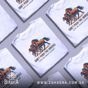 Футболка don't push the horses, білого кольору, зображена в групі з іншими футболками, фон світло-сірий, принт з трьома конями, кольори принта - коричневий, чорний та оранжевий, текст під принтом чорного кольору.
