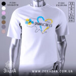 Футболка дружина воїна ЗСУ, білого кольору, зображена з фронтального ракурсу на манекені, фон світло-сірий, принт містить контур України з кольоровими серцями та написом.