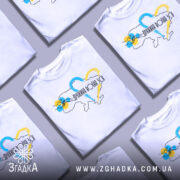 Футболка дружина воїна ЗСУ, білого кольору, зображена з фронтального ракурсу на манекені, фон світло-сірий, принт містить контур України з кольоровими серцями та написом.