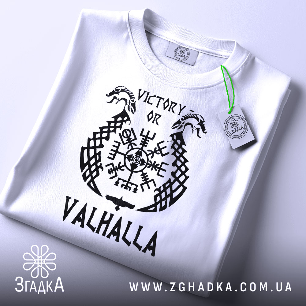 Футболка дух вікінга, біла, зображена зверху, на столі, фон світло-сірий, принт чорного кольору з написом 'VICTORY OR VALHALLA' та зеленим ярликом.