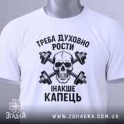 Футболка духовний ріст, білого кольору, складена на поверхні, фон світло-сірий, принт чорного кольору з черепом та гантелями, текст українською мовою, на етикетці зелена стрічка.