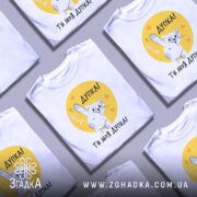 Футболка дупка ти моя, біла футболка з коротким рукавом, зображення кота, що показує лапкою, на жовтому фоні з сердечками, текст "Дупка! Ти моя дупка!" під принтом.