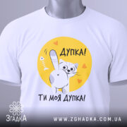 Футболка дупка ти моя, біла футболка, зображена зверху, принт з котом на жовтому фоні, текст "Дупка! Ти моя дупка!", з зеленим ярликом.