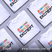 Футболка душніла токсік експерт, білого кольору, зображена з правого ракурсу на манекені, фон світло-сірий, принт кольоровий з написом 'Душніла токсік експерт' у різних шрифтах.