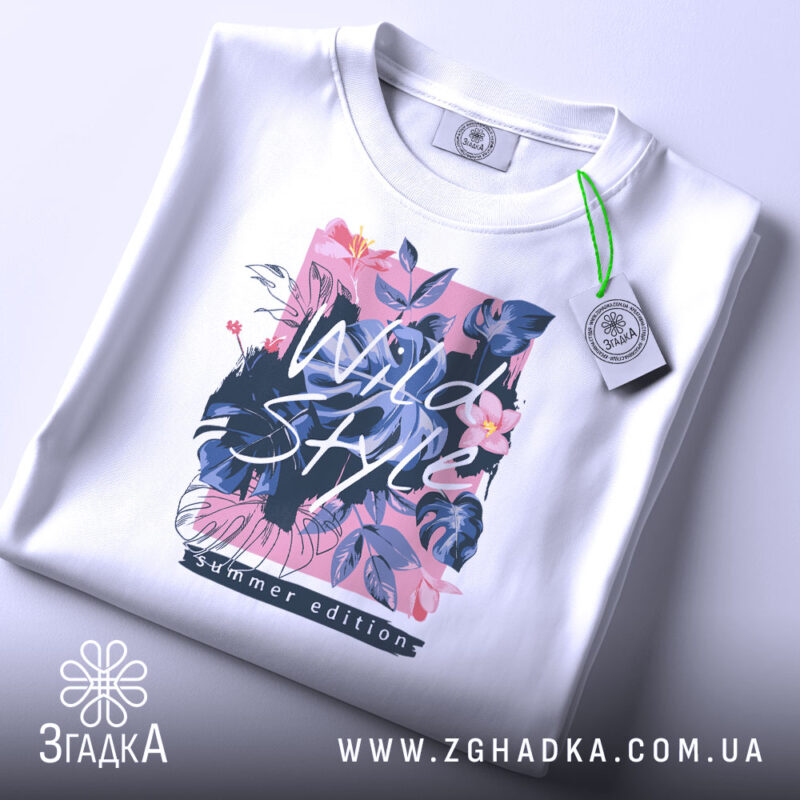 Футболка дикий стиль, біла, зображена зверху, фон світло-сірий, принт з квітами та написом 'Wild Style', на футболці є етикетка з зеленим шнурком.